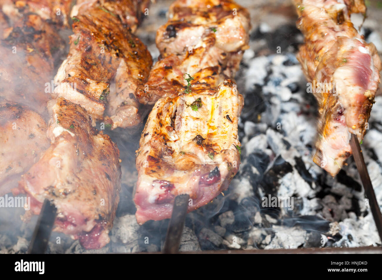 Orange succosi pezzi di carne durante la cottura maggiore Caucaso kebab su spiedini su un fuoco. Camping. La foto è stata scattata da vicino, piccole profondità di campo Foto Stock
