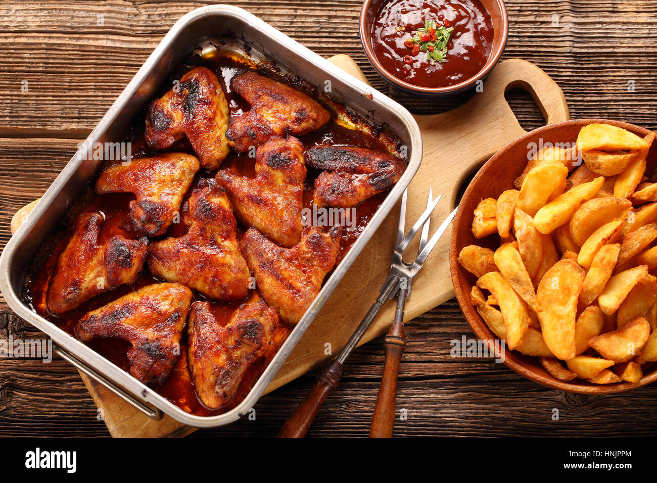 Ali di pollo al forno con patate e salsa barbecue su sfondo di legno Foto  stock - Alamy