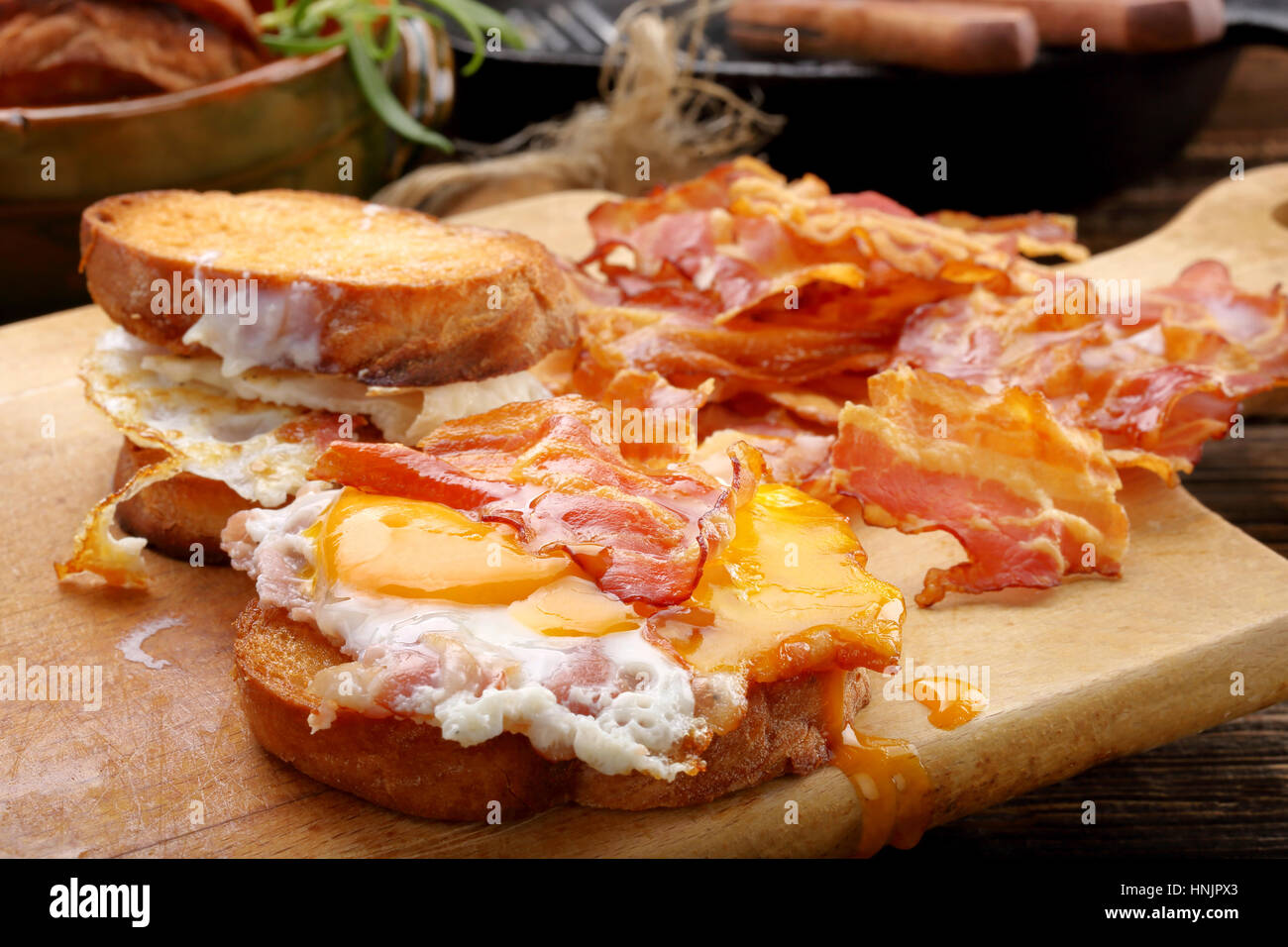 Sandwich con uova fritte e pancetta calda pezzi sullo sfondo di legno Foto Stock