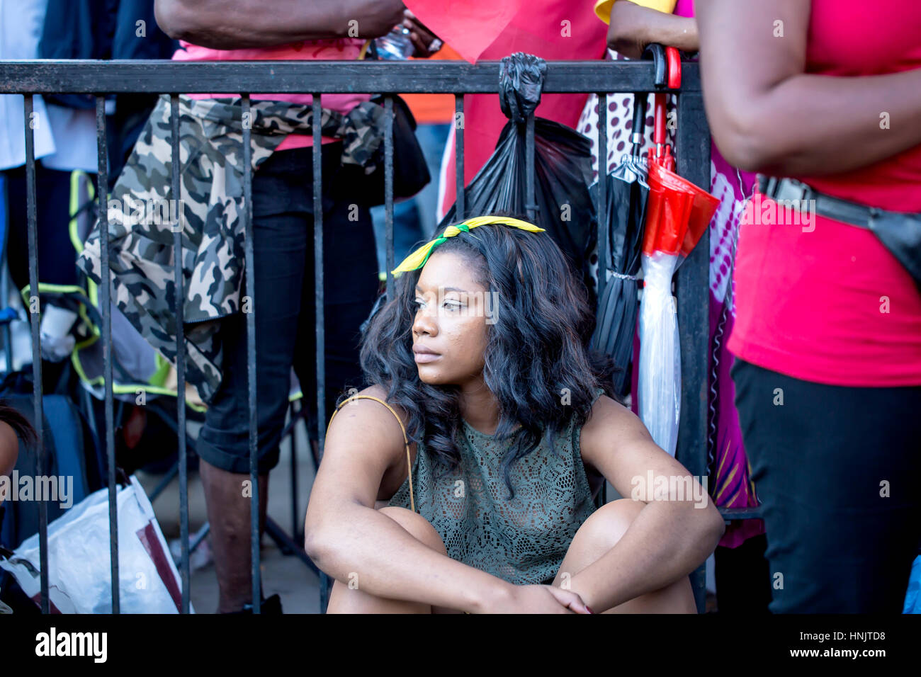 London, Regno Unito - 29 agosto 2016: spettatore al carnevale di Notting Hill. Una giovane donna è circondato da spettatori come si siede sul lato di Foto Stock