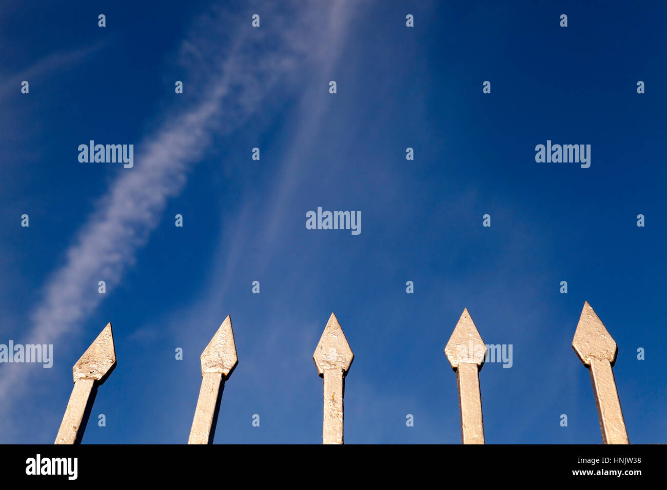 Parte di una recinzione metallica con picchi contro un cielo blu. Ingrandimento di foto Foto Stock