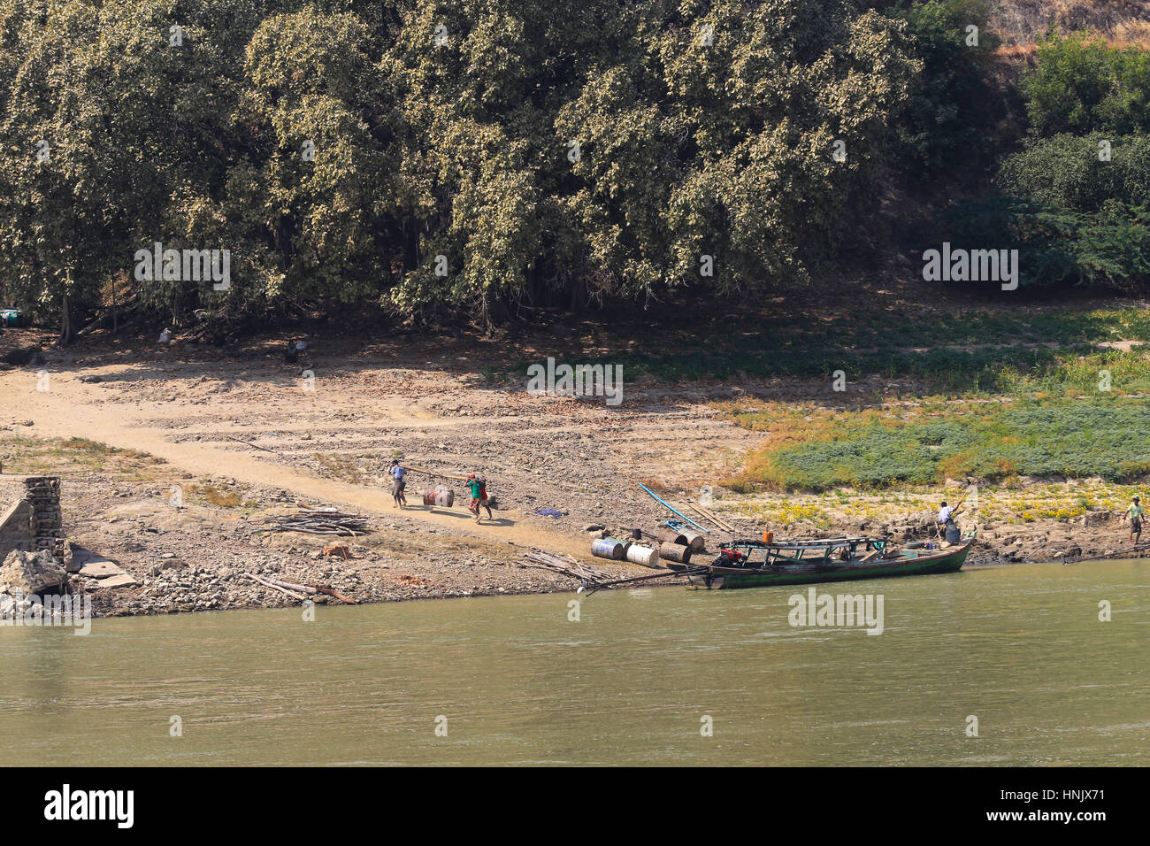 Quattro uomini trasportano una pesante 45 galloni canna in una imbracatura fino la riva del fiume da una barca da carico sul fiume Irrawaddy in Mandalay (Birmania). Foto Stock