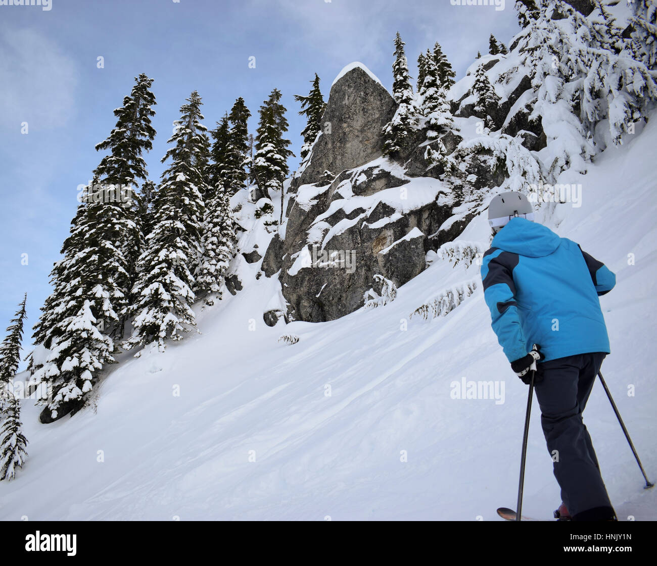Sciatore guardando il rock nevoso su una collina nevoso Foto Stock