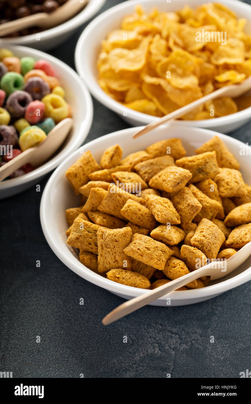 Varietà di cereali freddi in bianco ciotole con cucchiai di legno, veloce colazione per bambini Foto Stock