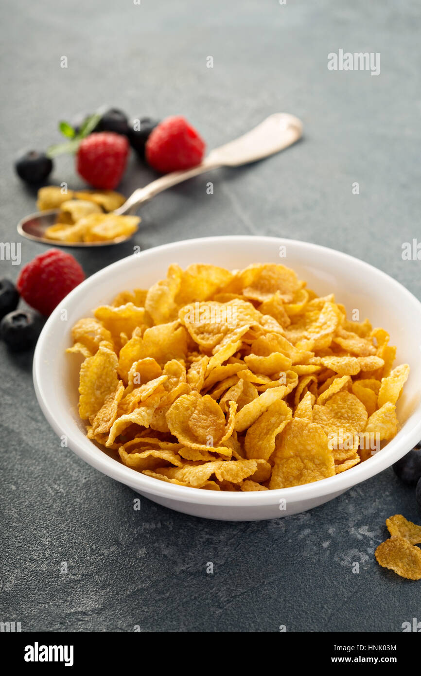 Cornflake cereali in una ciotola con cucchiaio su sfondo blu, colazione veloce Foto Stock
