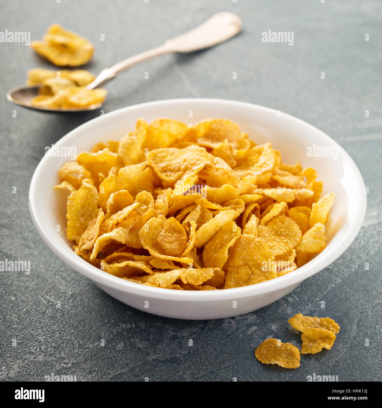 Cornflake cereali in una ciotola con cucchiaio su sfondo blu, colazione veloce Foto Stock