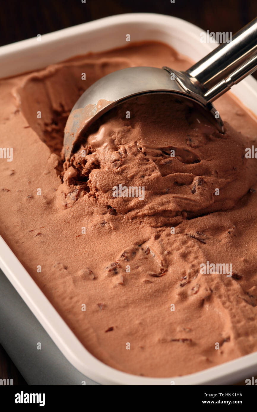 Foto di un metallo scoop scavando in una vasca di gelato al cioccolato. Foto Stock