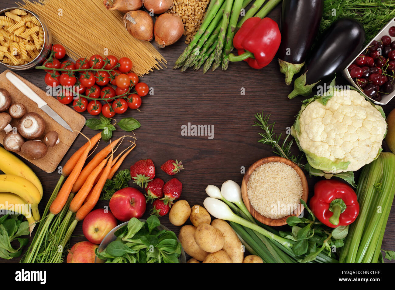 Foto di un tavolo pieno di verdure fresche, frutta e altri cibi sani con uno spazio in mezzo per il testo. Foto Stock