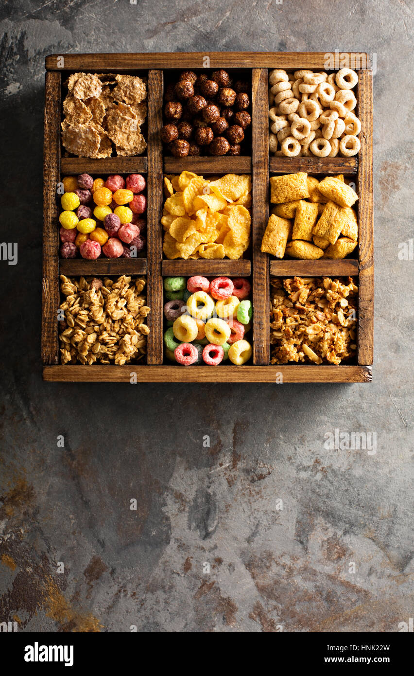 Varietà di cereali freddi in una scatola di legno, veloce colazione per bambini overhead shot Foto Stock