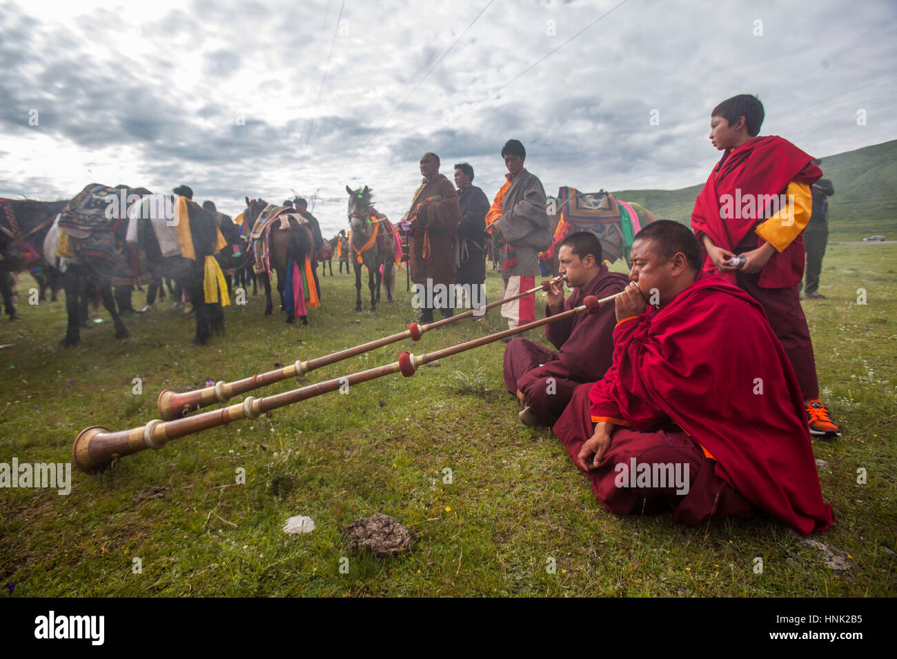 Monaci buddisti tibetani riprodurre strumenti tradizionali di benedire i piloti del Cavallino prima racing al Manigango Horse Festival alta nella Platea tibetano Foto Stock