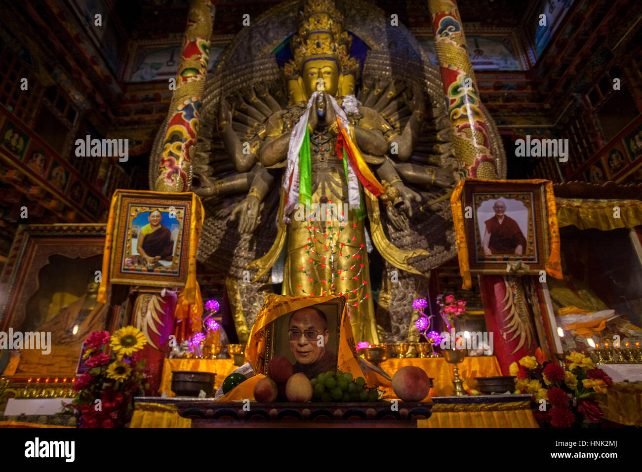 Una foto del Dalai Lama si appoggia ai piedi di una statua nel monastero Tagong nell'altopiano tibetano regione in Sichuan, in Cina. Foto Stock
