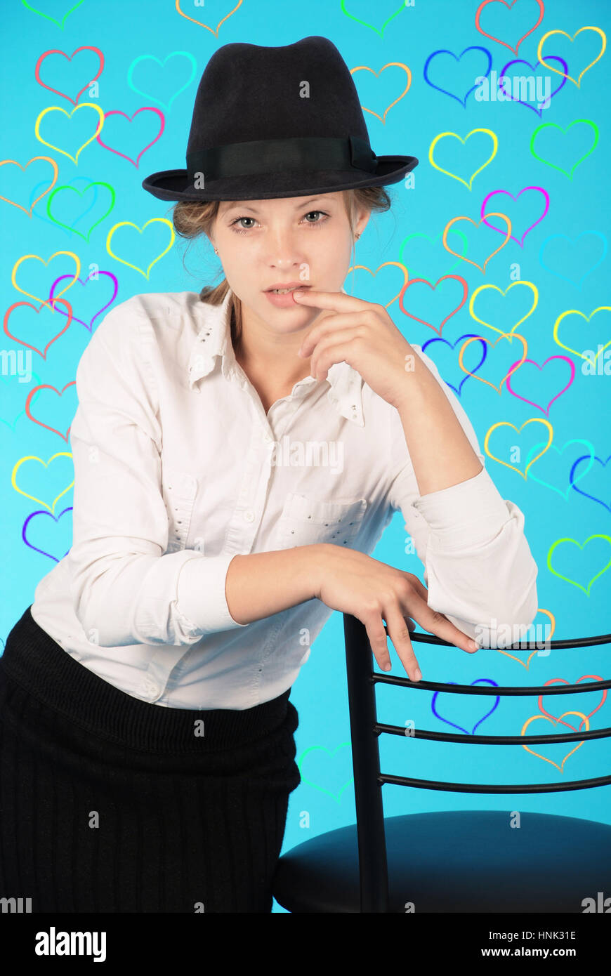 Giovane ragazza si siede su una sedia isolato su blu Foto Stock