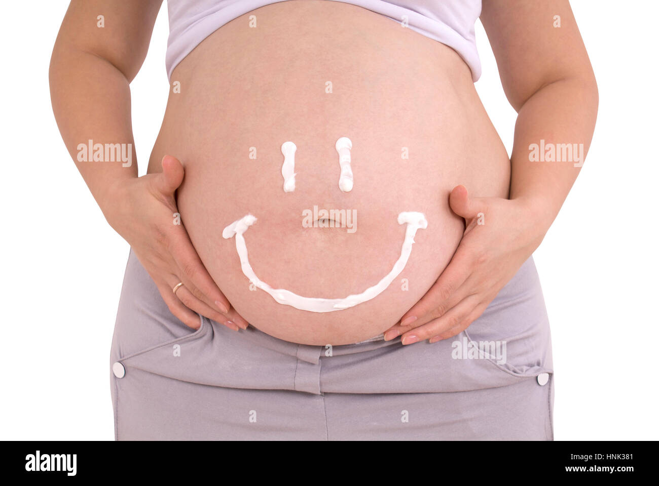 La cura per la gravidanza pelle della pancia. Sorriso dipinto sul ventre di  una donna incinta con una crema per smagliature isolato con il percorso  Foto stock - Alamy