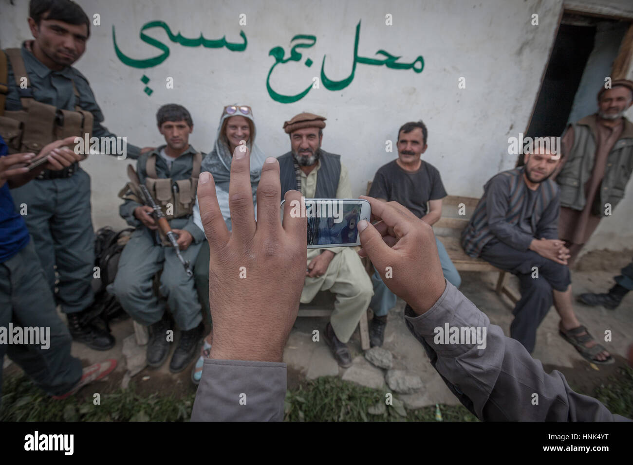 Afghanistan, Wakhan corridor, un turista con militari afghani seduto su una panchina al di fuori della stazione di polizia, che posano per una foto di gruppo. Foto Stock