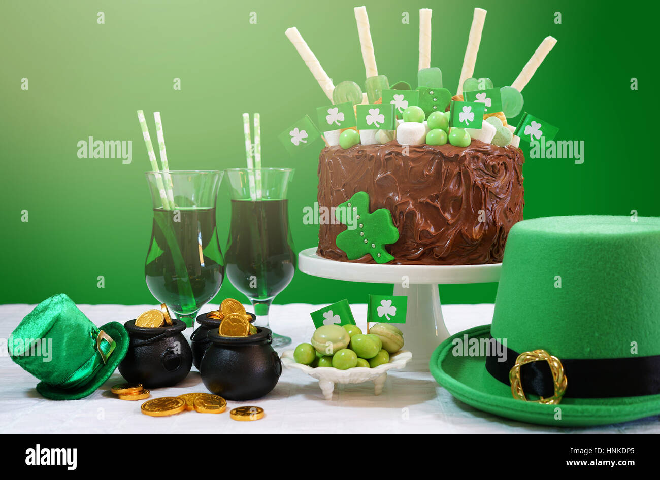 Felice il giorno di San Patrizio, 17 marzo, verde e bianco tavola partito impediva di procedere con una torta al cioccolato decorata con caramelle, biscotti e shamrock bandiere. Foto Stock