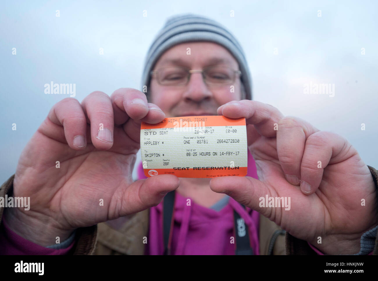 Un uomo che sostiene il suo biglietto per il Tornado locomotiva a Appleby stazione prima si tira il primo calendario di linea principale a vapore e servizio di bolina per mezzo secolo attraverso il viadotto Ribblehead nel North Yorkshire. Foto Stock