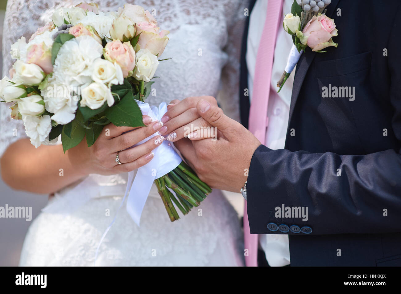 Lo sposo tiene il suo spose in mano e un mazzo di nozze Foto Stock