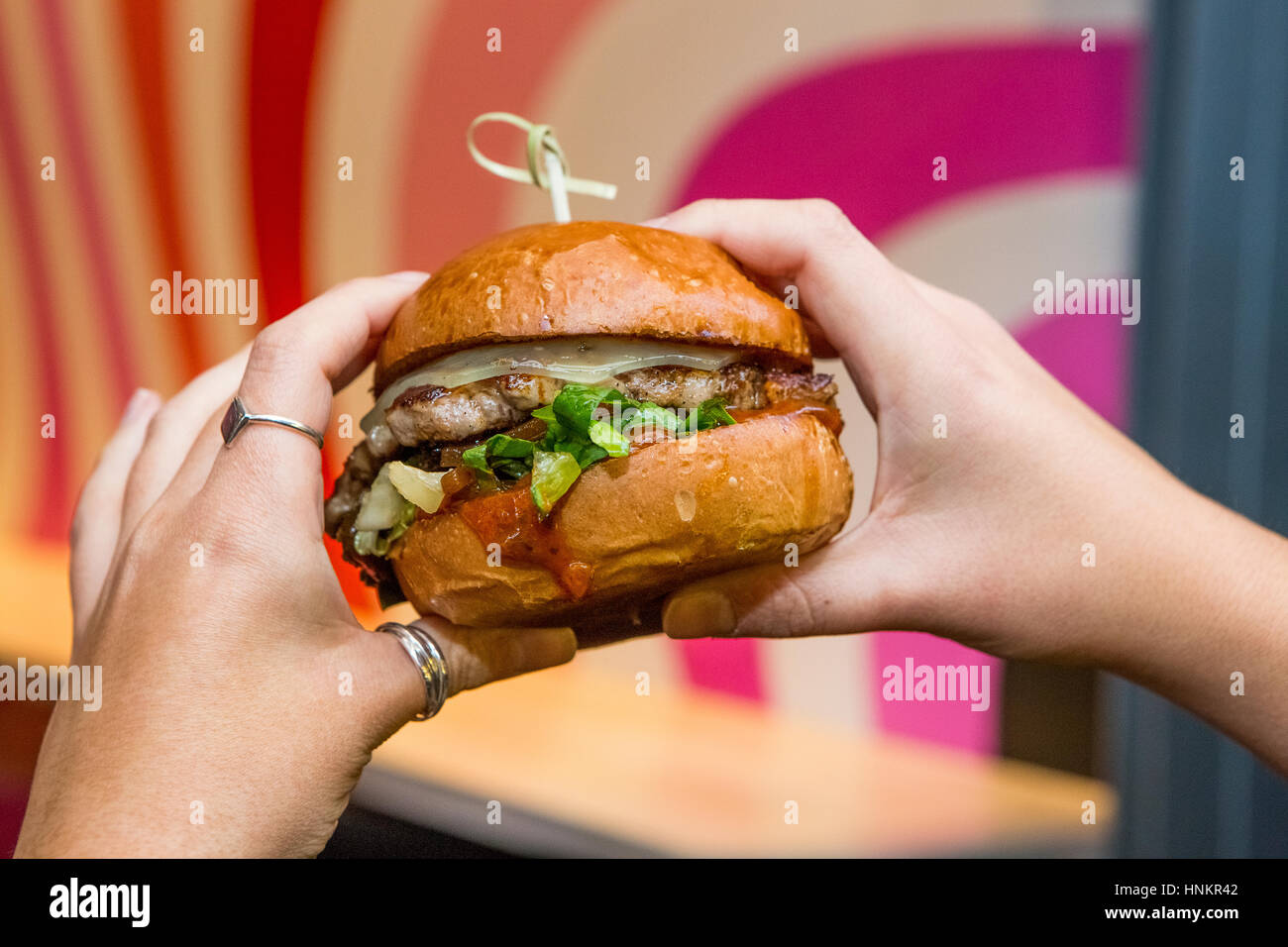 Cheeseburger tenuto in mano womans. Foto Stock