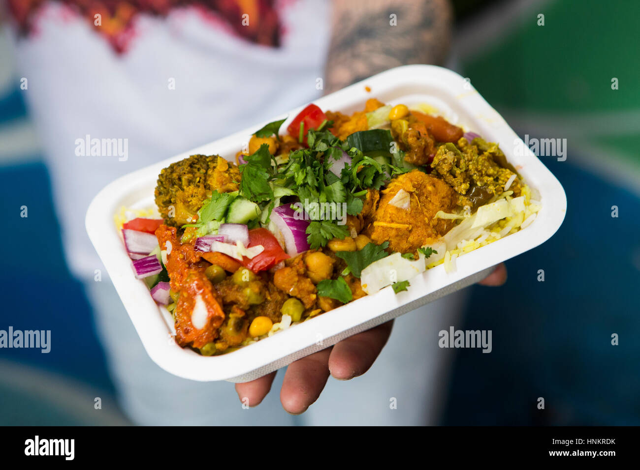 Curry vegetariano, street food, detenute da uomo con tatuaggio. Foto Stock