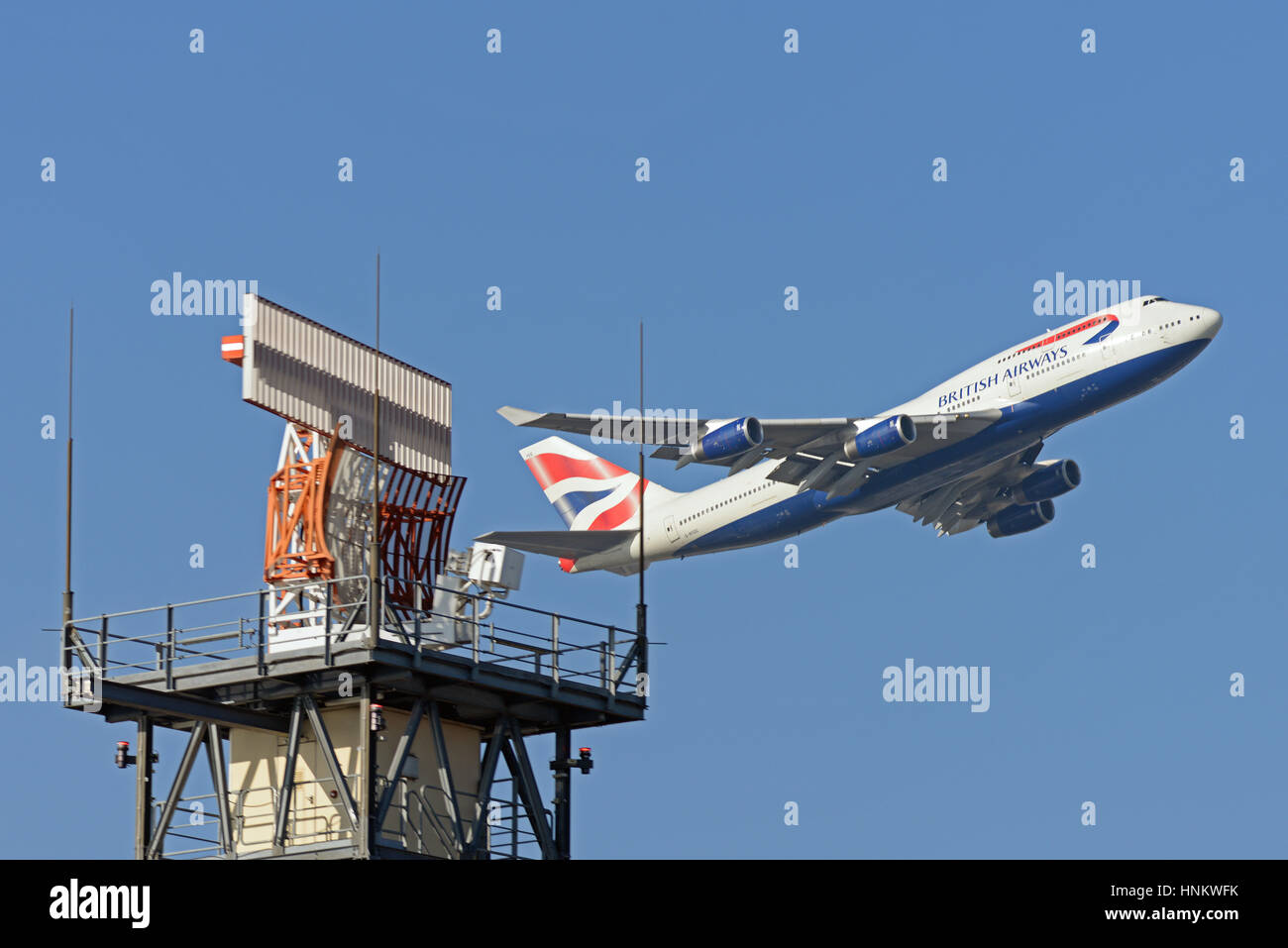 Lo spazio aereo controllato. British Airways 747 G-BYGG decollo dall'Aeroporto di Londra Heathrow in cielo blu passando il controllo del traffico aereo antenna radar Foto Stock