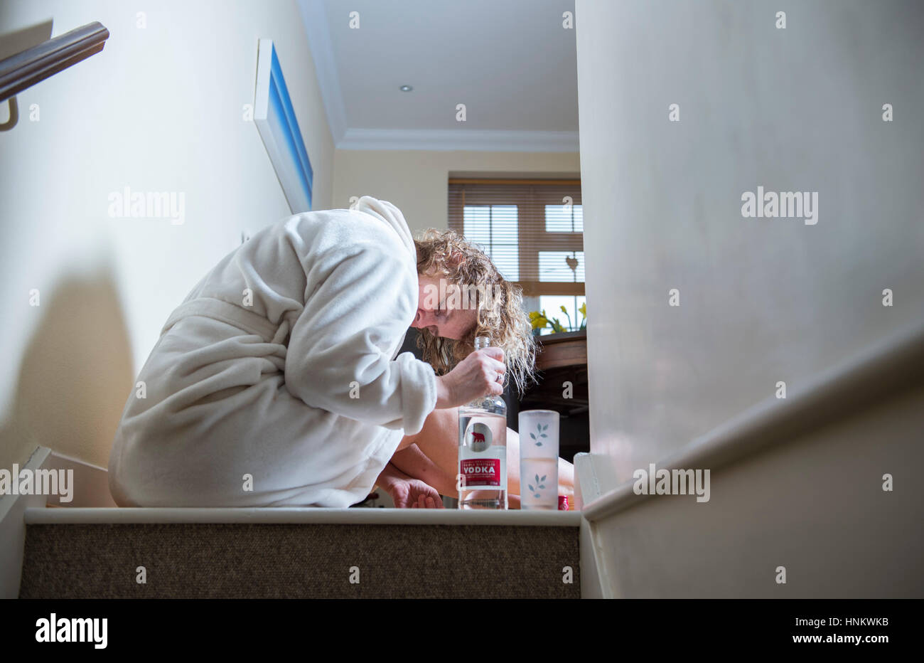 Premuto donna seduta nella sua vestaglia a casa durante il giorno pesantemente bere al self médicale - Fotografia poste dal modello Foto Stock
