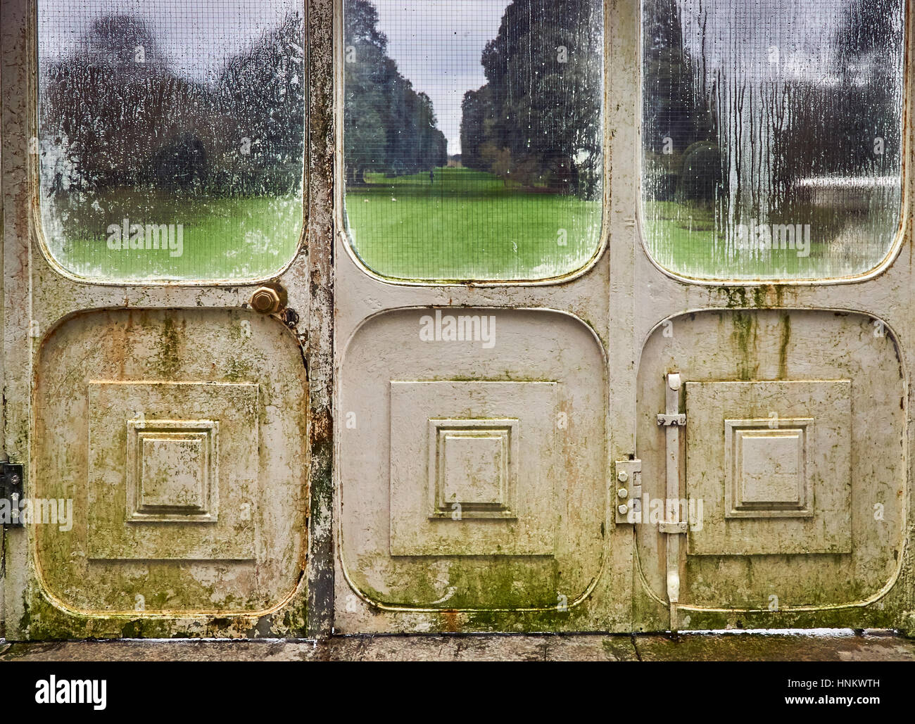 Le porte di un vetro vittoriano conservatorio guardando verso un parco vista esterna Foto Stock