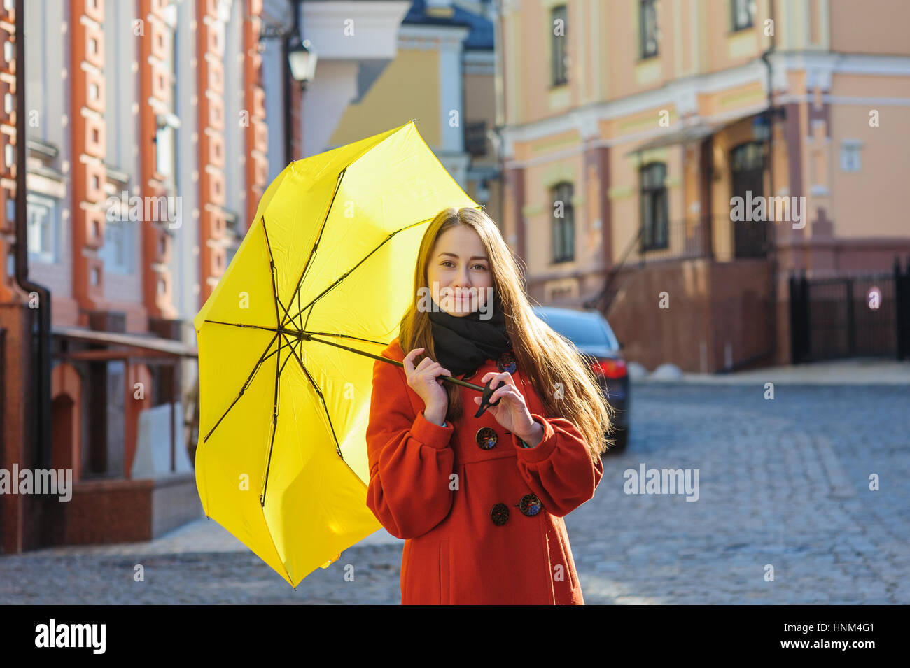Giovane donna con un ombrello giallo a piedi in strada Foto Stock