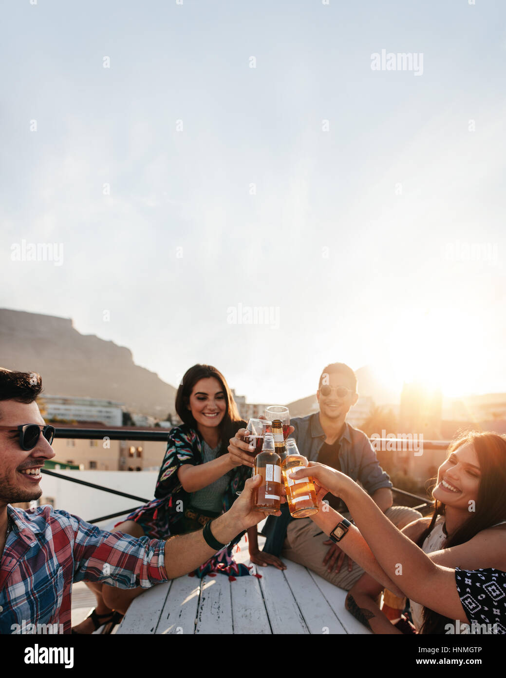 Felice giovani celebrando con bevande a parte sul tetto. Giovani amici appendere fuori e godersi un drink. Foto Stock Felice giovani celebrando con bevande a parte sul tetto. Giovani amici appendere fuori e godersi un drink. Foto Stock