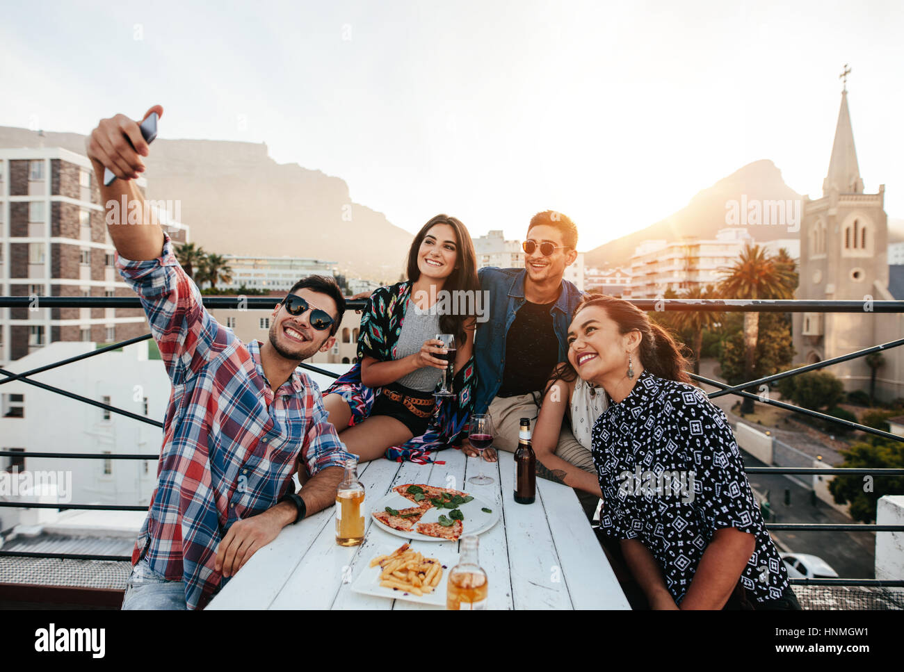 Gruppo di amici avente una parte sul tetto facendo una selfie. Felice giovani prendendo ritratto di auto durante il party. Foto Stock Gruppo di amici avente una parte sul tetto facendo una selfie. Felice giovani prendendo ritratto di auto durante il party. Foto Stock