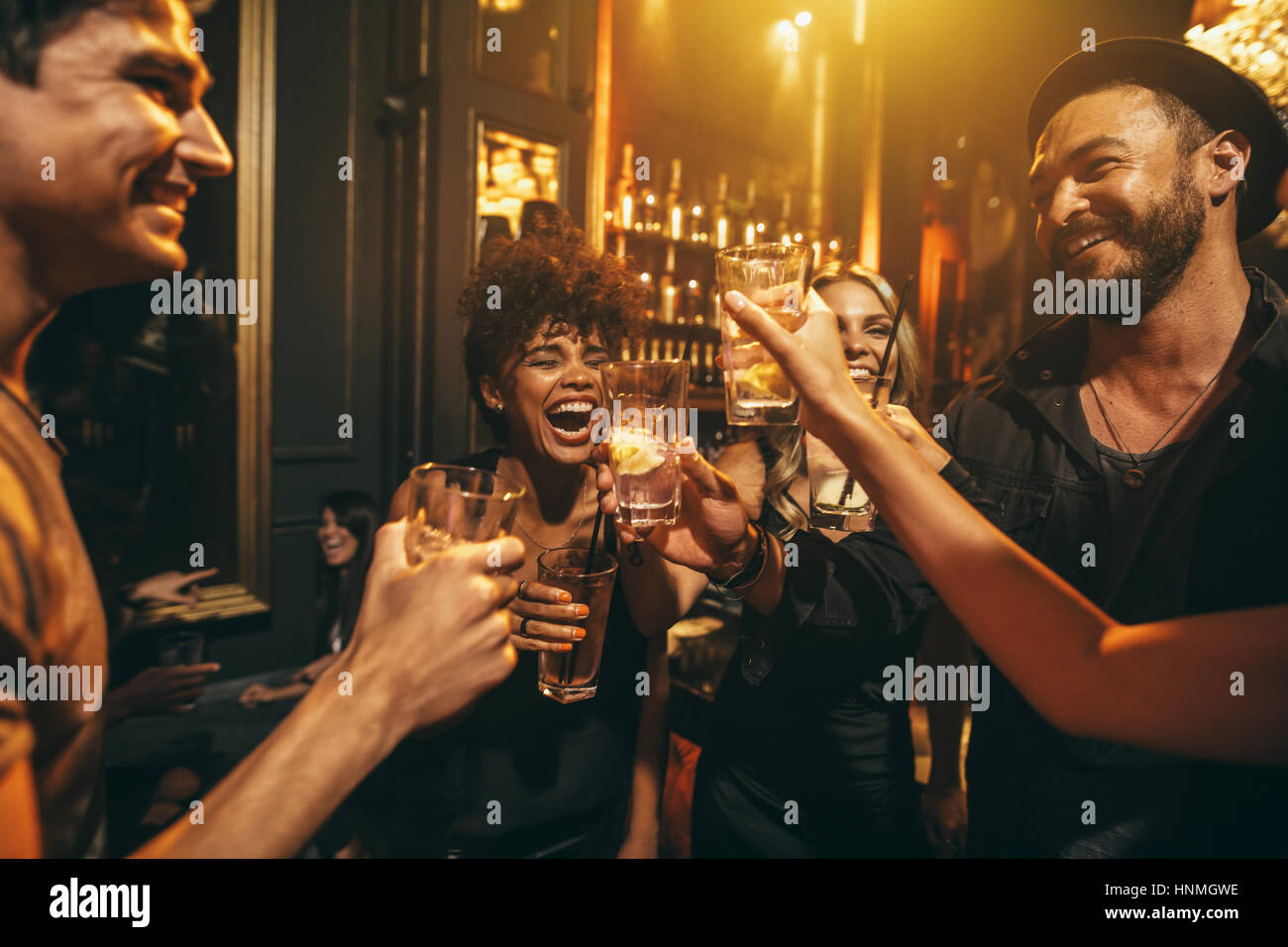 Colpo di giovani uomini e donne godendo di un partito. Gruppo di amici avente bevande al night club. Foto Stock Colpo di giovani uomini e donne godendo di un partito. Gruppo di amici avente bevande al night club. Foto Stock