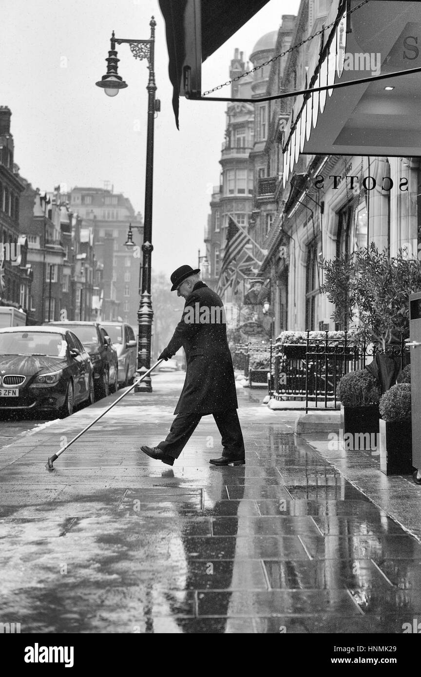 Ristorante Concierge spazzando neve dalla porta. Foto Stock