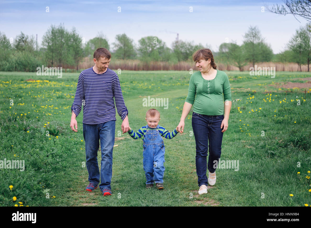 Famiglia giovane e giovane figlio a piedi su un prato a molla Foto Stock