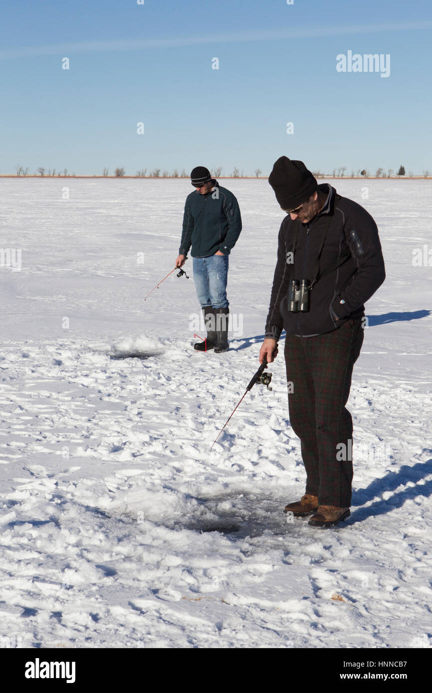 Gli uomini di stand in corrispondenza dei fori nel ghiaccio come sagoma per walleye. Foto Stock