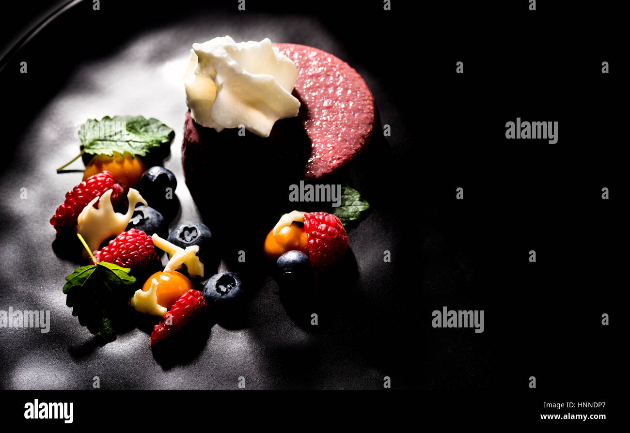 Crema di vino con mousse di frutta fresca sulla piastra scuro dessert spazio per il layout del testo Foto Stock