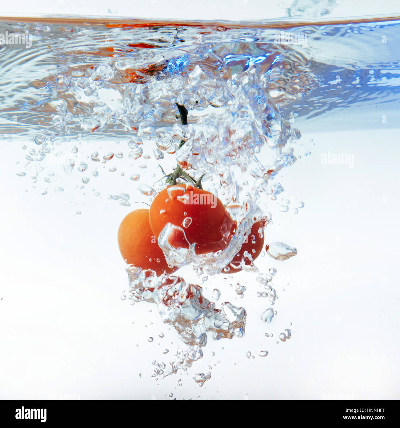 Freschi pomodori ciliegia con acqua splash isolato su bianco backgr Foto Stock