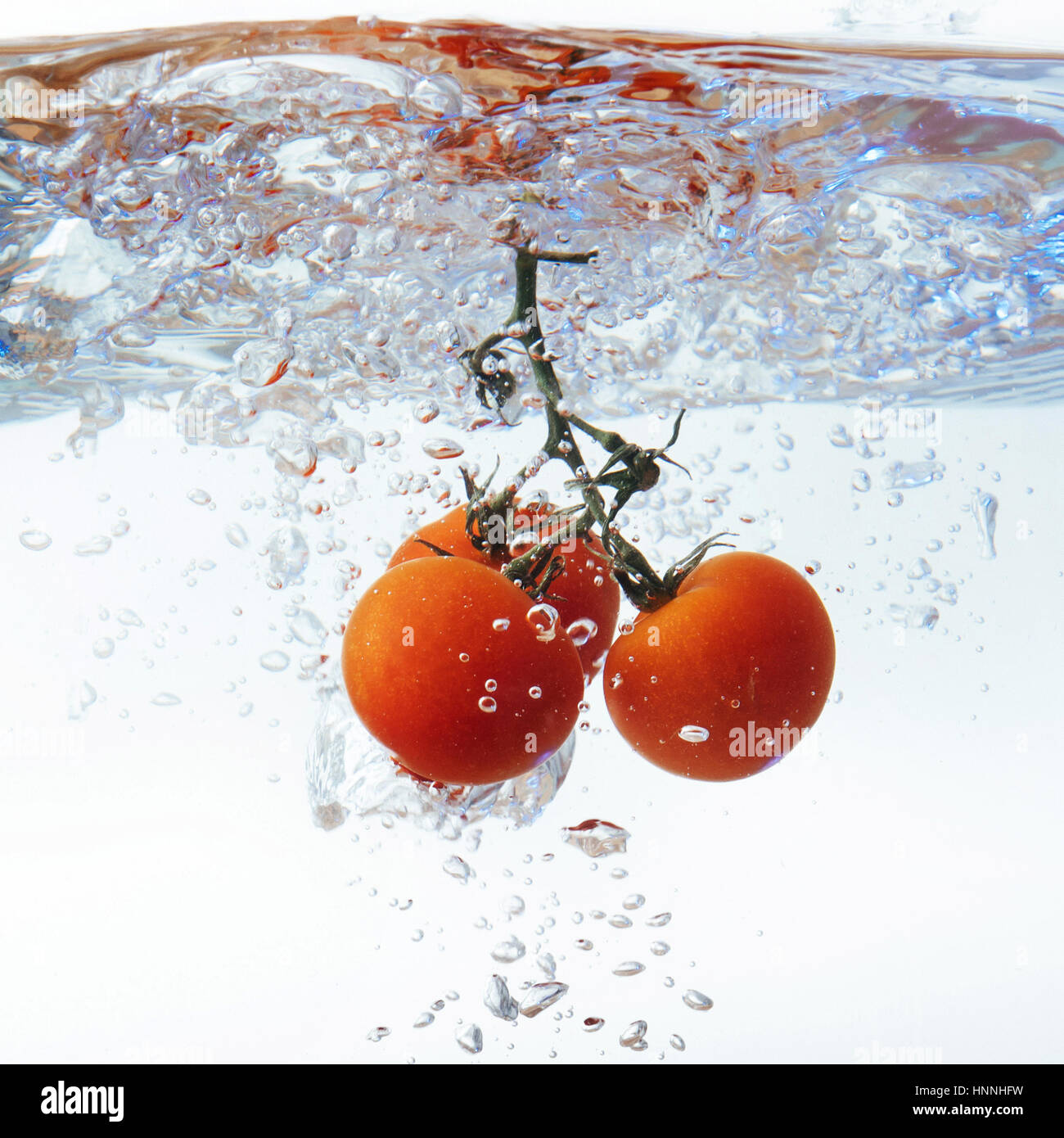 Freschi pomodori ciliegia con acqua splash isolato su bianco backgr Foto Stock