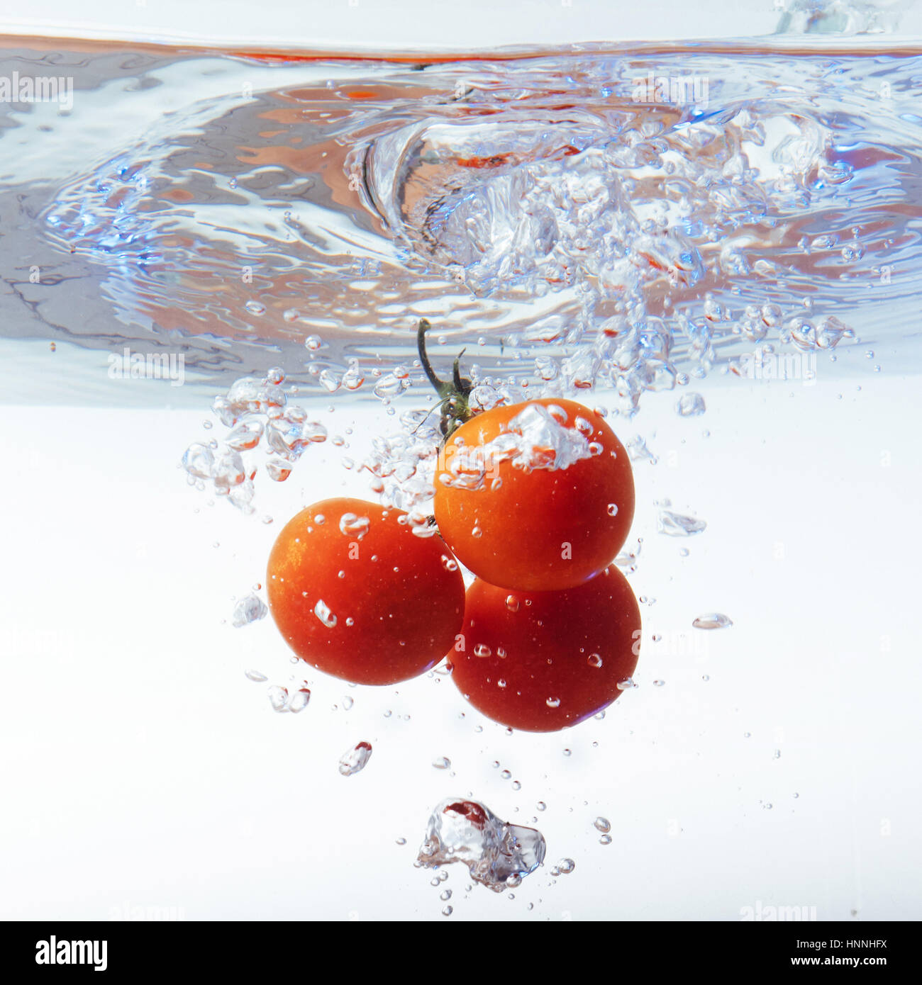 Freschi pomodori ciliegia con acqua splash isolato su bianco backgr Foto Stock
