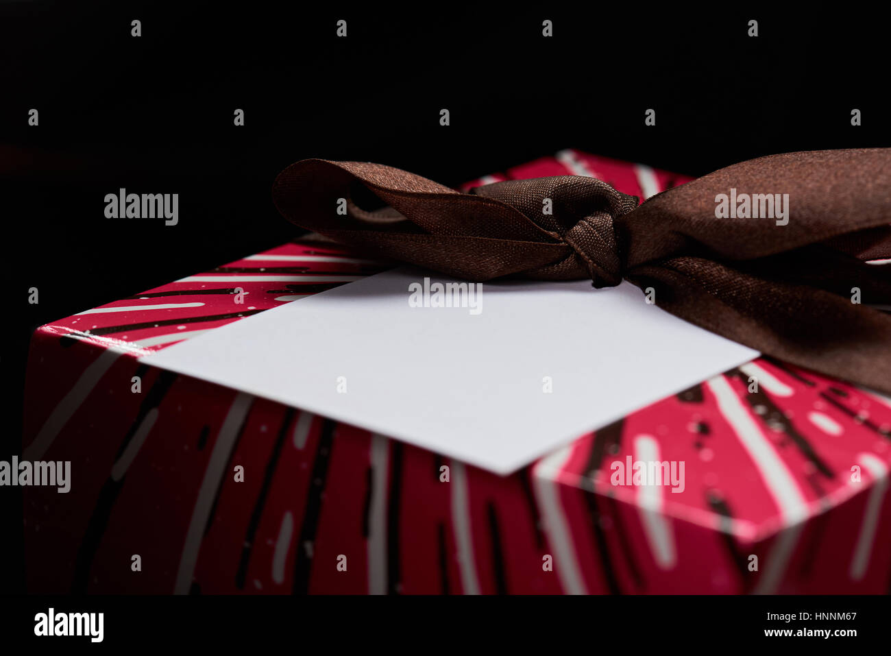 Libro bianco etichetta sulla confezione regalo con nastro marrone isolati su sfondo nero Foto Stock