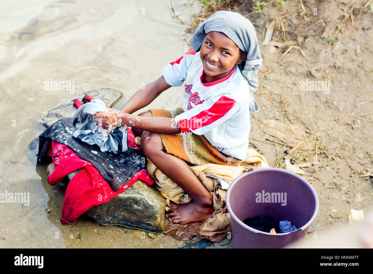 Giovane ragazza malgascio a lavare i panni nel fiume in Madagascar Foto Stock