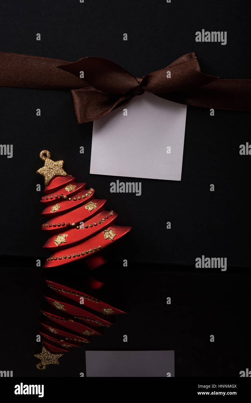 Messaggio di Natale sul tag di carta marrone con nastro. Decorazione di Natale rosso giocattolo ad albero Foto Stock