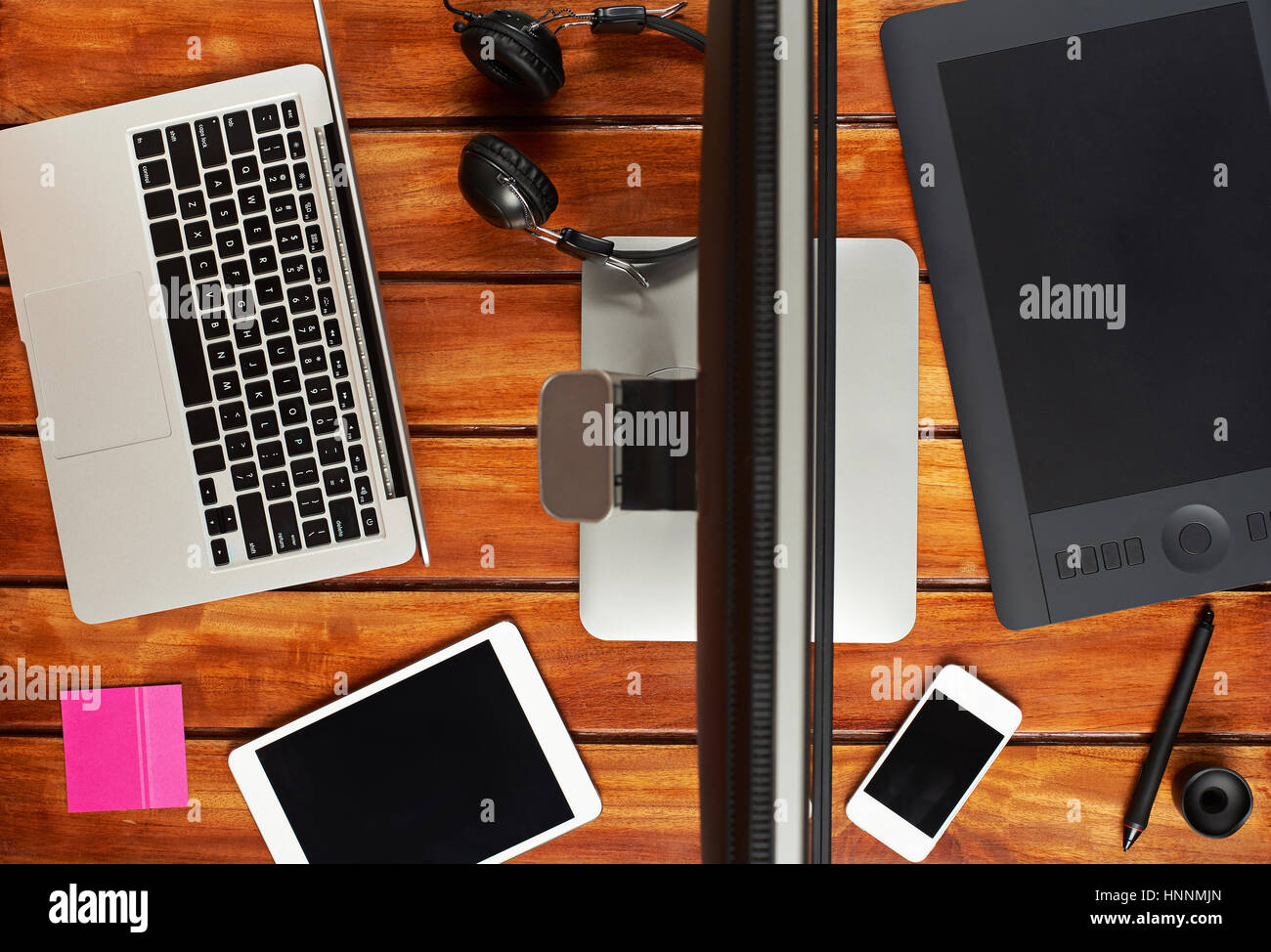 Luogo di lavoro di design studio vista dall'alto su legno marrone tabella. Laptop, tablet, smartphone,pen,cuffie sulla scrivania di legno Foto Stock