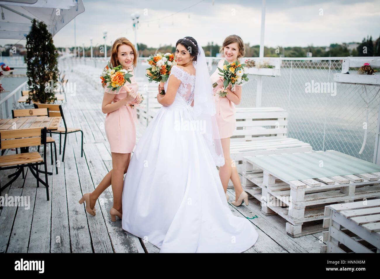 Sposa con bridesmaids poste sul molo di attracco a nuvoloso giorno di nozze. Foto Stock