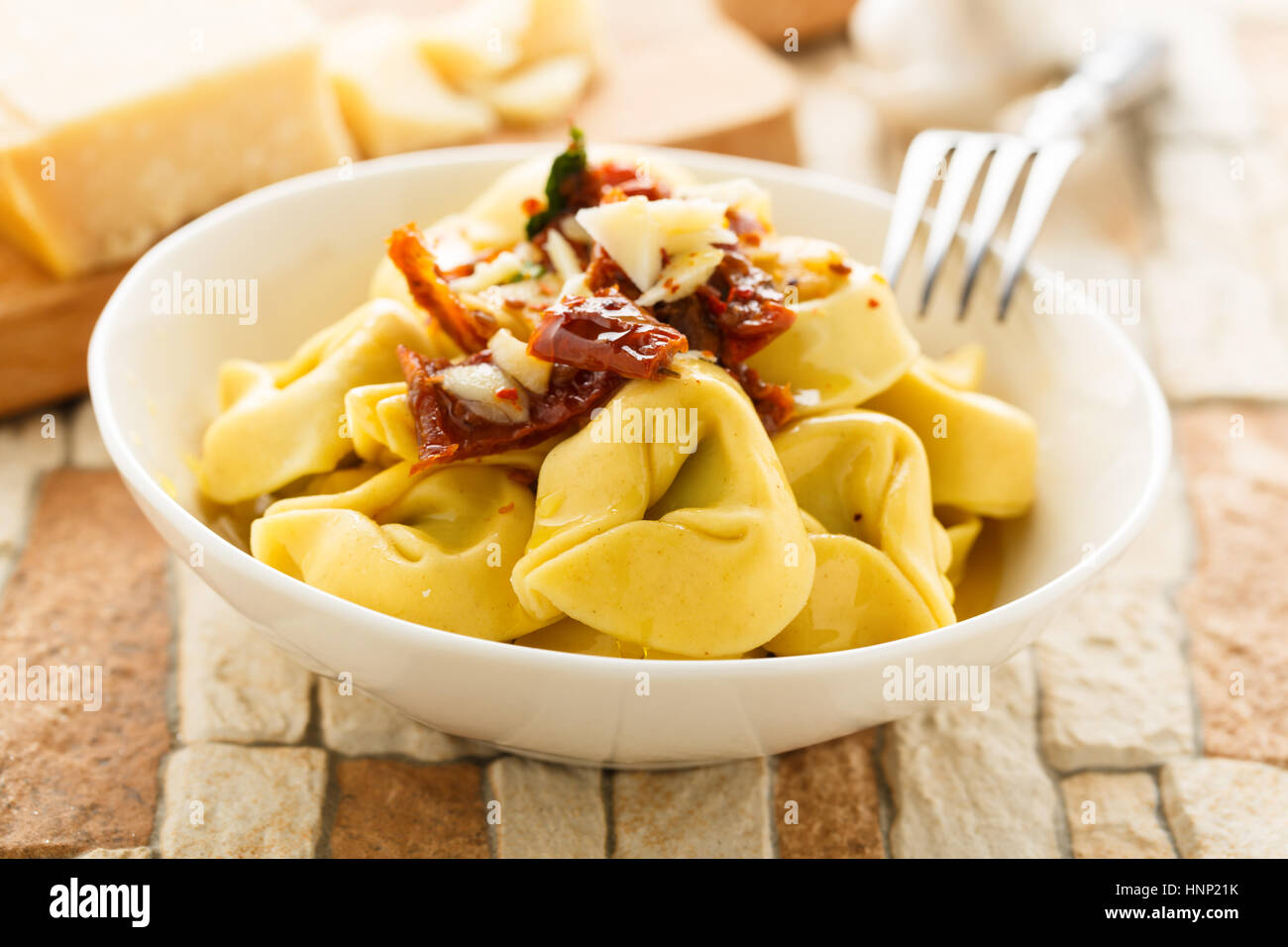 Tortelloni di aglio, olio e peperoncino con pomodori secchi, parmigiano e  basilico Foto stock - Alamy