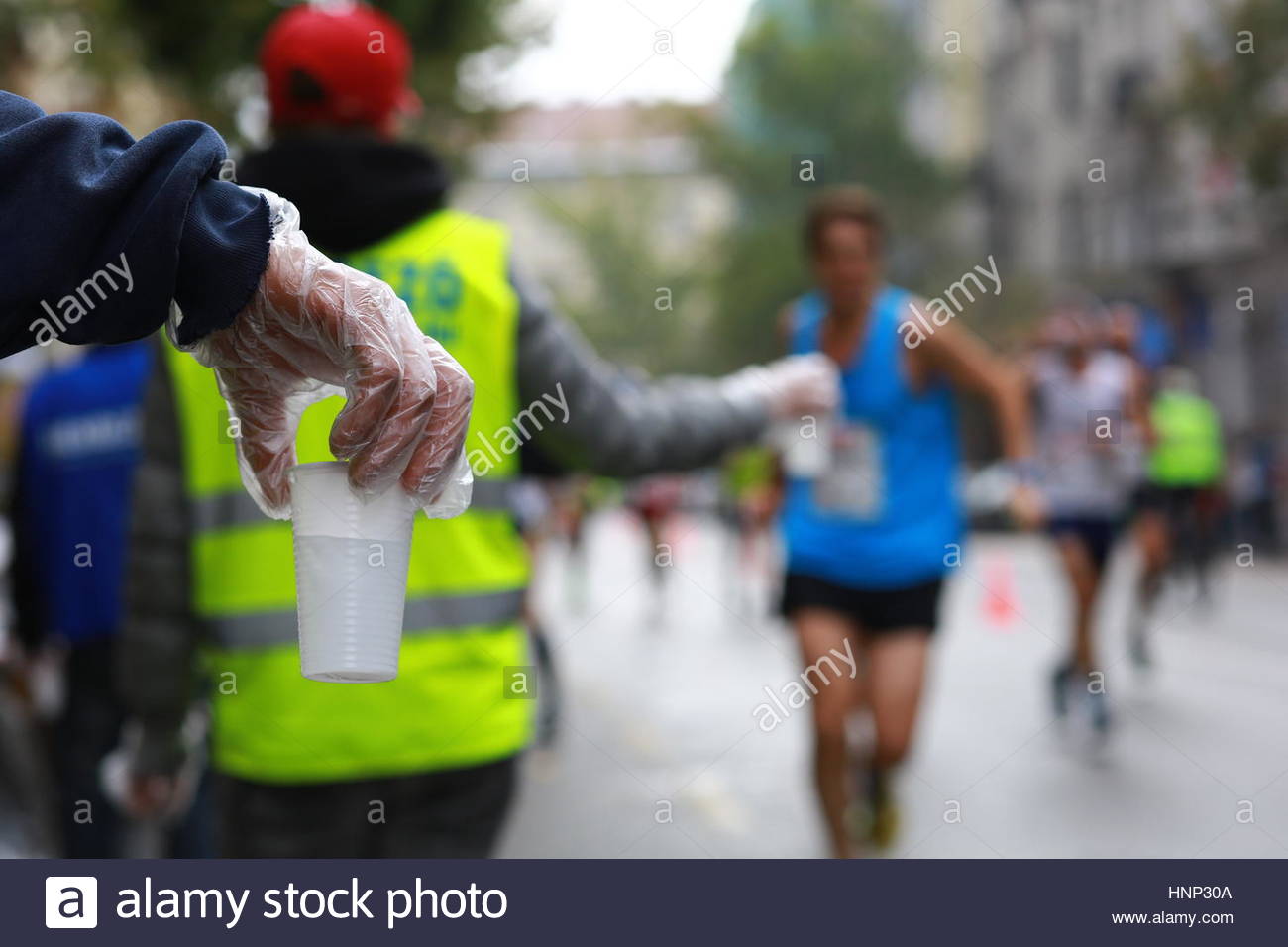 Un volontario offre una tazza di acqua per guide di scorrimento in corrispondenza di una maratona nel centro della citta'. Foto Stock