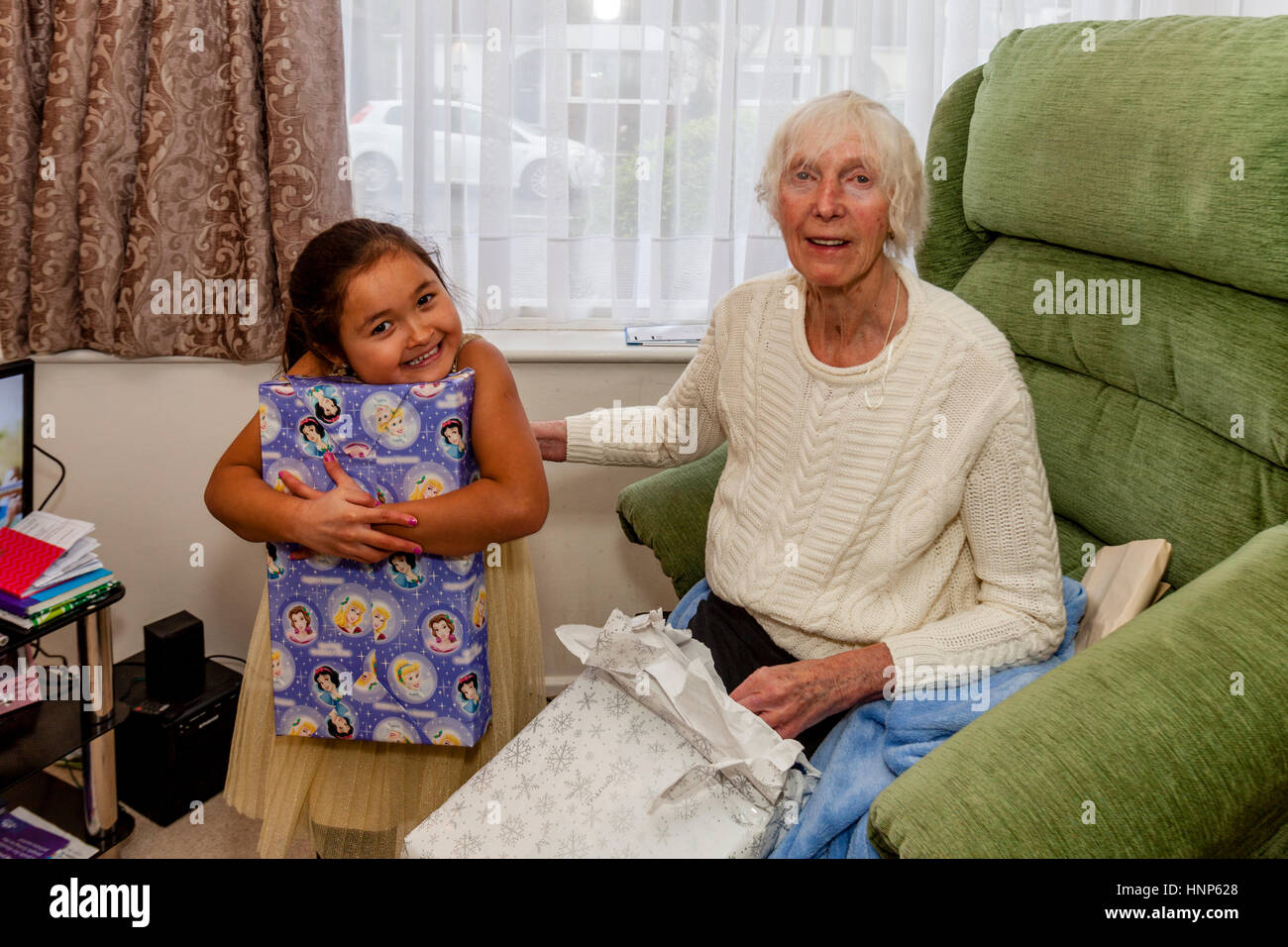 Una razza mista di bambino e sua nonna apertura presenta il giorno di Natale, Sussex, Regno Unito Foto Stock