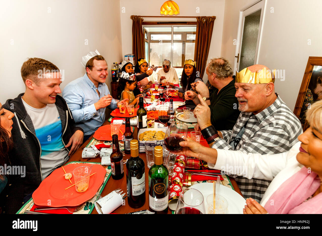Un multi etnico famiglia sedersi ad un tradizionale pranzo di Natale, Sussex, Regno Unito Foto Stock