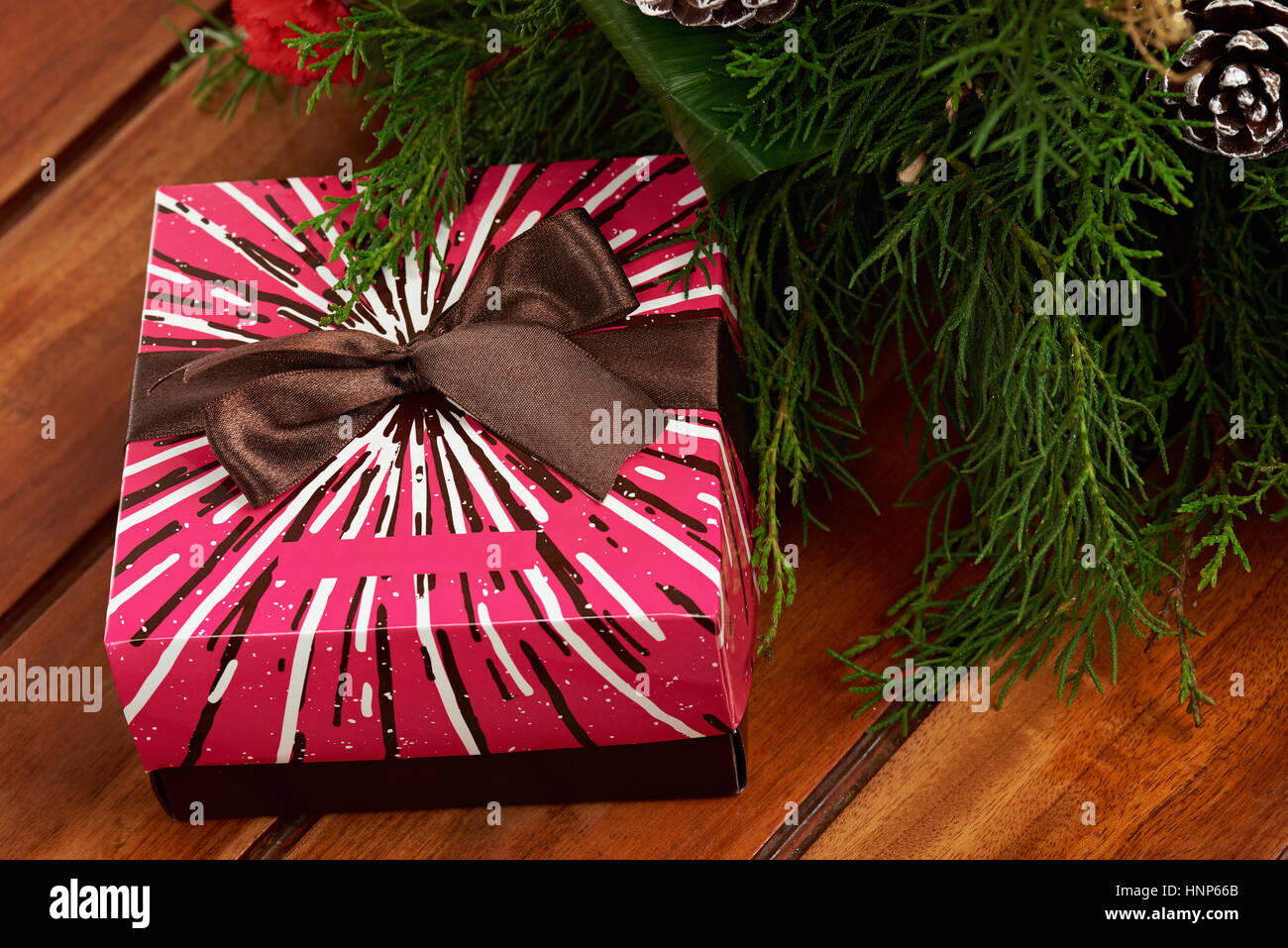 Marrone sul nastro rosa casella colorata con decorazione di Natale sfondo di legno Foto Stock