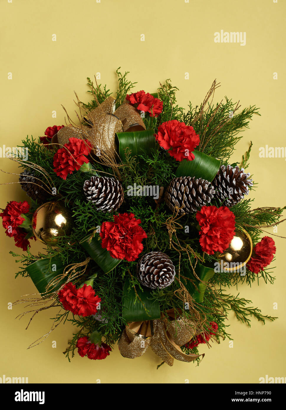 Pino decorazione di Natale con fiori di colore rosso isolato su sfondo giallo Foto Stock