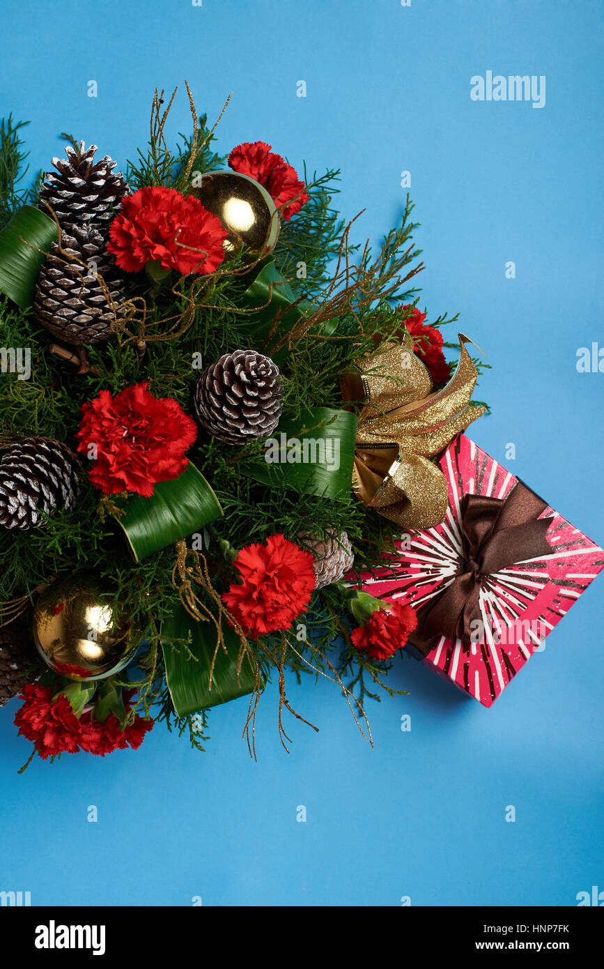 Natale decorazioni di fiori con scatola regalo isolato su sfondo blu Foto Stock