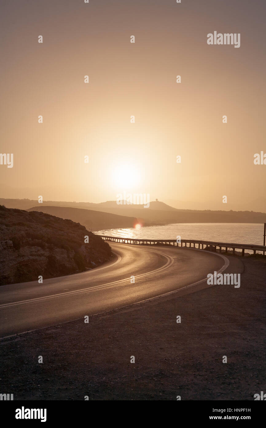 Un avvolgimento su strada asfaltata dal mare la voce off in un tramonto sulle colline Foto Stock